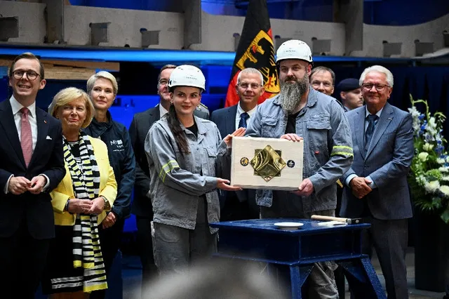 Empleados de Rheinmetall sostienen una placa conmemorativa de colocación de la quilla, flanqueados por el director ejecutivo de Rheinmetall Armin Papperger, el ministro de Estado alemán para la Cooperación con los Estados Federados Philipp Amthor, el ministro de Defensa Boris Pistorius y la ministra principal de Mecklemburgo-Pomerania Occidental y candidata principal del SPD Manuela Schwesig, durante una ceremonia de colocación de la quilla en el astillero de Rheinmetall en Wolgast, Alemania, el 14 de septiembre de 2026.